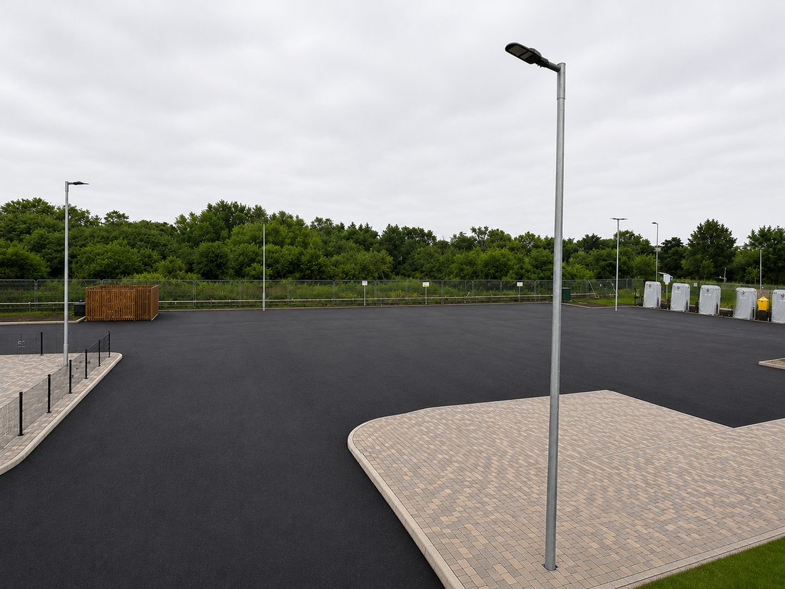 Newly surfaced asphalt drive-thru and parking area with block-paved islands and lighting columns at a retail site in Hertfordshire